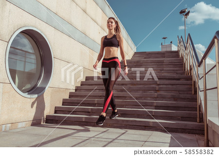 Sports girl goes in summer city. Sportswear Leggings Top. Step background. Motivation for fitness 58558382