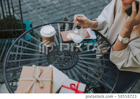 Female with a cellphone enjoying dessert outdoors 58558723