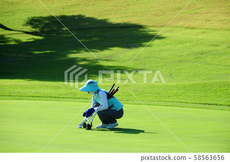 Caddy working on a golf course green Caddy working on a golf course green 58563656