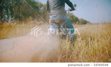 Biker is riding a bike on the road on the field Biker is riding a bike on the road on the field 58569594