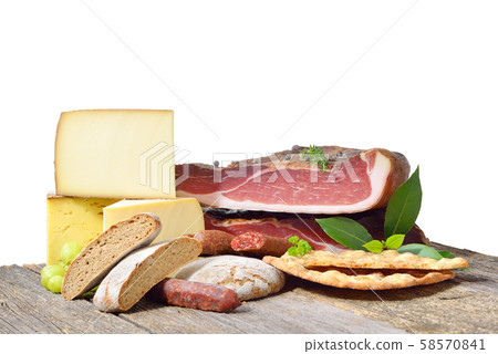 South Tyrolean specialties like bacon, sausages and cheese lying in front of a white background 58570841