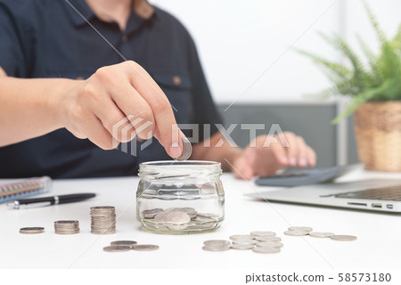 Man holding coins putting in glass Man holding coins putting in glass 58573180