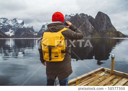 Portrait traveler man talking on mobile phone. Tourist in a yellow backpack standing on a background 58577308