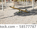 Wooden seesaw in a public park on a summer afternoon surrounded by trees 58577787