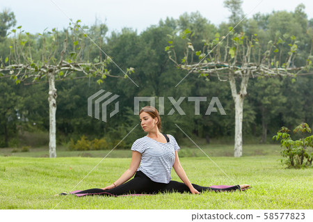 Young beautiful woman doing yoga exercise in green park. Healthy lifestyle and fitness concept. 58577823
