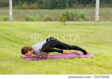 Young beautiful woman doing yoga exercise in green park. Healthy lifestyle and fitness concept. 58578086