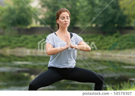 Young beautiful woman doing yoga exercise in green park. Healthy lifestyle and fitness concept. Young beautiful woman doing yoga exercise in green park. Healthy lifestyle and fitness concept. 58578307