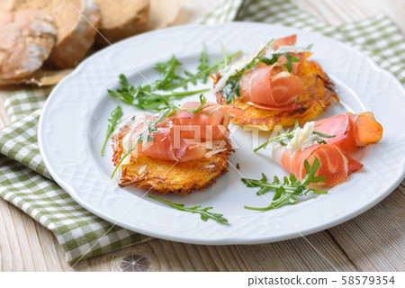 Potato rosti with South Tyrolean bacon, parmesan cheese and rocket salad served on a white plate Potato rosti with South Tyrolean bacon, parmesan cheese and rocket salad served on a white plate 58579354