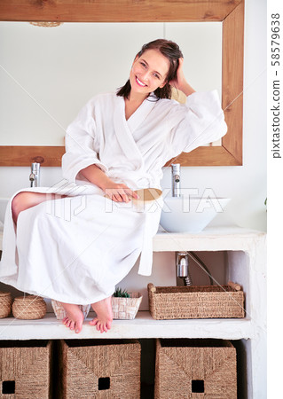 Image of young brunette woman with comb and wet hair sitting in bath. 58579638