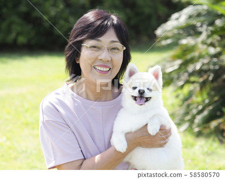 Smiling senior woman embracing dog 58580570