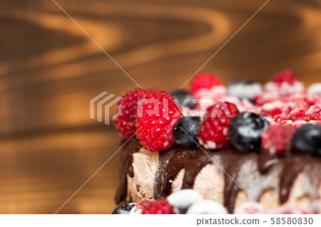 A close-up view of vegan chocolate cake covered with raspberries and blueberries, frozen in the A close-up view of vegan chocolate cake covered with raspberries and blueberries, frozen in the 58580830