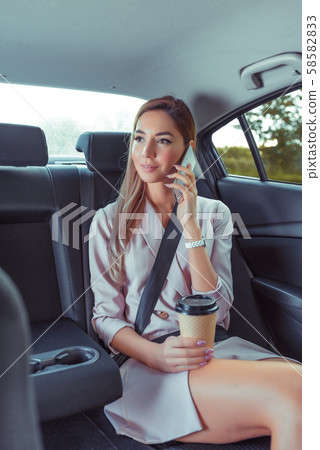 Business woman in car taxi, pink tanned leather suit, ringing on cell phone, meeting friends 58582833