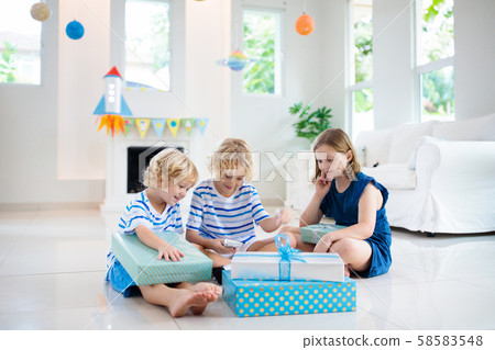 Space theme kids birthday party. Boy with present. 58583548