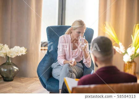 Woman drinking water while feeling emotional sharing problems 58584313