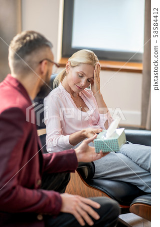 Woman having headache while speaking with psychologist 58584412