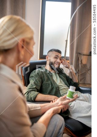 Bearded man smiling while speaking with psychoanalyst 58584495