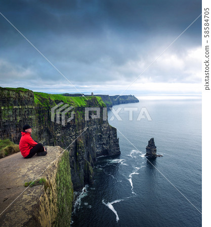 Hiker sitting at the cliffs of Moher 58584705
