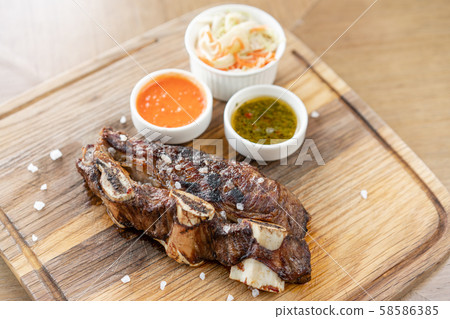 Beef meat cut according to the Argentine style, called asado. with Pickled cabbage and two sauces 58586385
