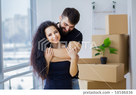 Couple showing keys to new home hugging looking at camera Couple showing keys to new home hugging looking at camera 58586836