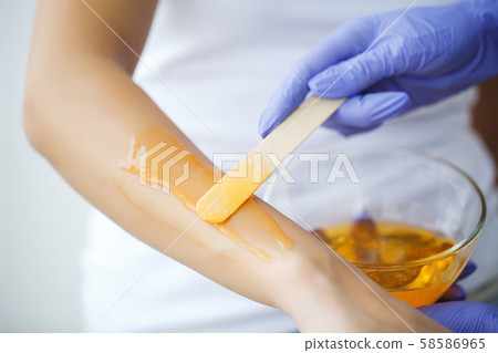 Master does epilation of hands with help of sugar paste hot wax in salon beauty. Master does epilation of hands with help of sugar paste hot wax in salon beauty. 58586965