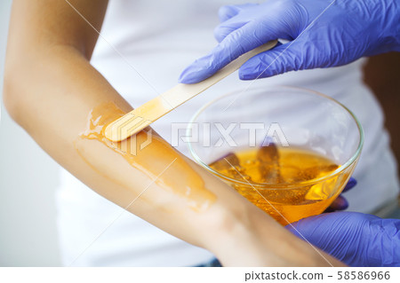 Master does epilation of hands with help of sugar paste hot wax in salon beauty. 58586966