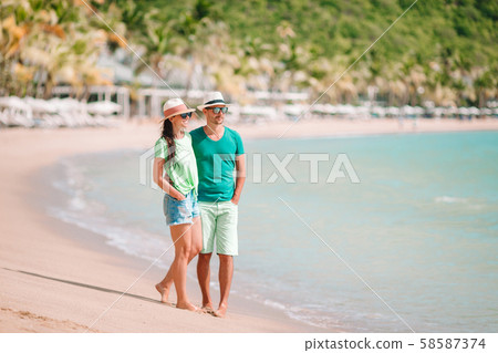 Young couple walking on tropical beach with white sand and turquoise ocean water at Antigua island Young couple walking on tropical beach with white sand and turquoise ocean water at Antigua island 58587374