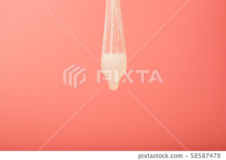 Condom that missed a drop of sperm, used contraceptive on a red background. Soft contrast 58587478