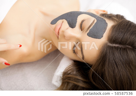 Spa therapy for young woman having facial mask at beauty salon - indoors 58587536