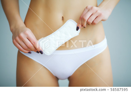 Young beautiful woman holding a menstruation cotton tampon and gasket in her hand, in a blurred 58587595