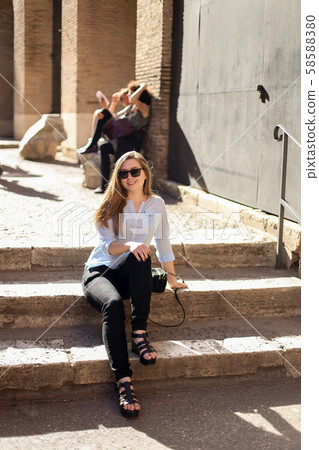 Young female tourist sitting on stairs inside Colosseum, Italy. Young female tourist sitting on stairs inside Colosseum, Italy. 58588380
