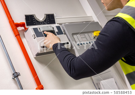 Male Technician Checking Smoke Detector In Datacenter Male Technician Checking Smoke Detector In Datacenter 58588453
