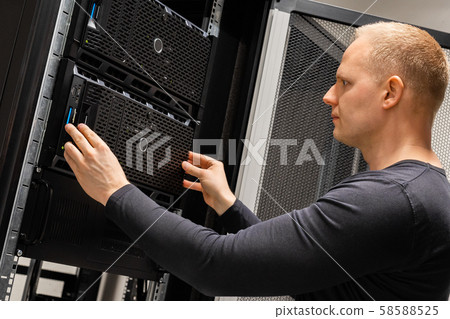 Male Technician Installing Servers In Enterprise Datacenter for Cloud Hosting 58588525