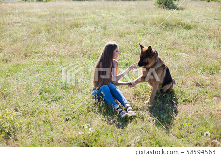 Woman trains German Shepherd in park on walk 58594563