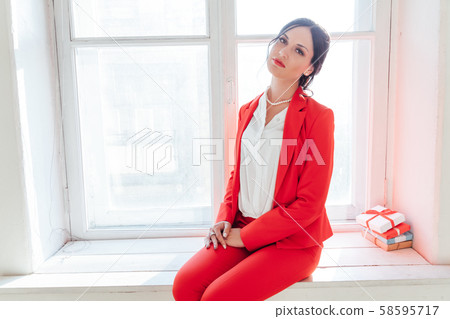 Beautiful brunette woman sits on the window sill by the window with gifts 58595717