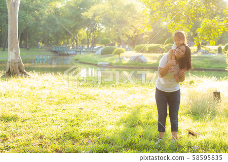 Beautiful young asian mother carrying little daughter with smile Beautiful young asian mother carrying little daughter with smile 58595835