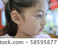 Adorable little Asian girl having ear piercing process. 58595877