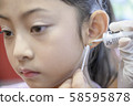 Adorable little Asian girl having ear piercing process. 58595878