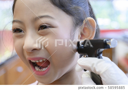 Adorable little Asian girl having ear piercing process. Adorable little Asian girl having ear piercing process. 58595885
