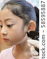 Adorable little Asian girl having ear piercing process. 58595887