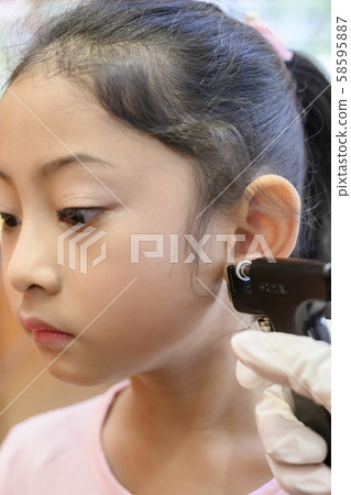 Adorable little Asian girl having ear piercing process. Adorable little Asian girl having ear piercing process. 58595887