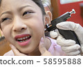 Adorable little Asian girl having ear piercing process. 58595888