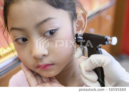 Adorable little Asian girl having ear piercing process. 58595889