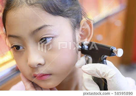 Adorable little Asian girl having ear piercing process. Adorable little Asian girl having ear piercing process. 58595890