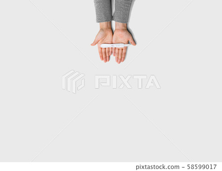 Woman holding a positive pregnancy test 58599017