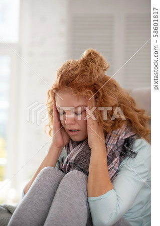 Woman wearing grey leggings touching head having awful headache Woman wearing grey leggings touching head having awful headache 58601817
