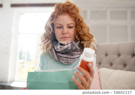 Red-haired young woman reading prescription for medication 58602157