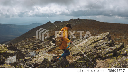 adventureous young man in green hat, yellow raincoat exploring nature 58603727