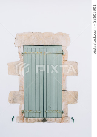 Old window with wooden light green painted shutters 58603901