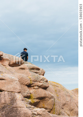 Young man on top of rock formations in Brittany Young man on top of rock formations in Brittany 58603903