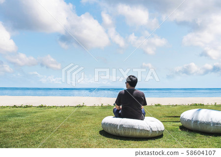 a man meditating on meadow at the beach in summertime a man meditating on meadow at the beach in summertime 58604107